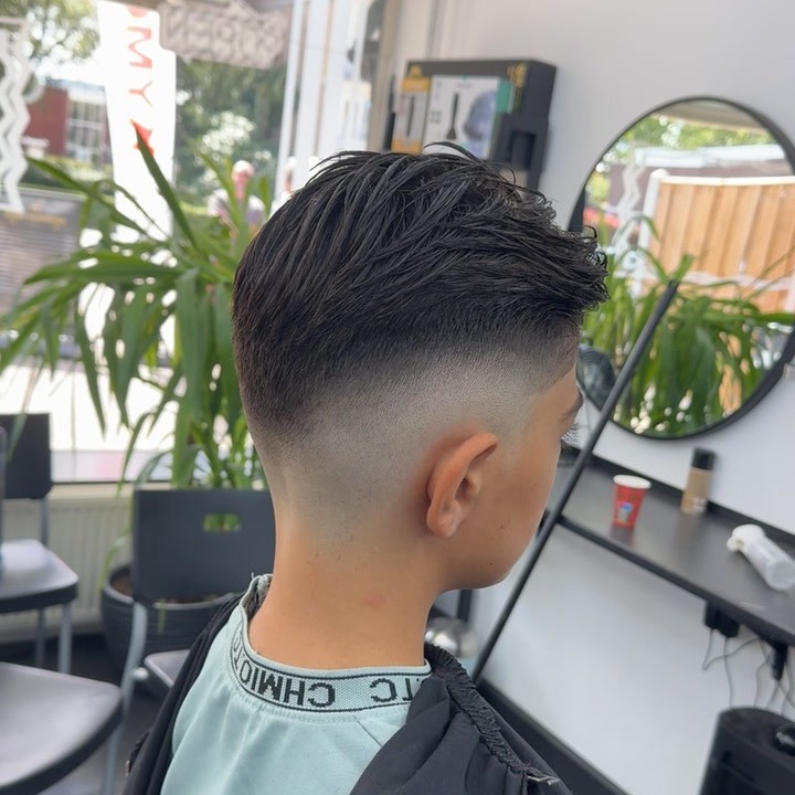 Skin fade van opzij, met de ronde spiegel en de plant van de zaak erachter
